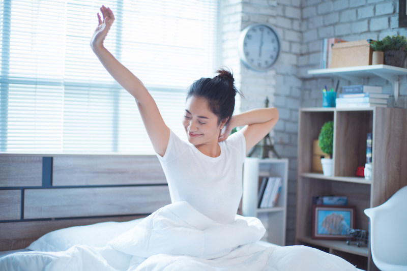 A woman waking up and stretching in bed.